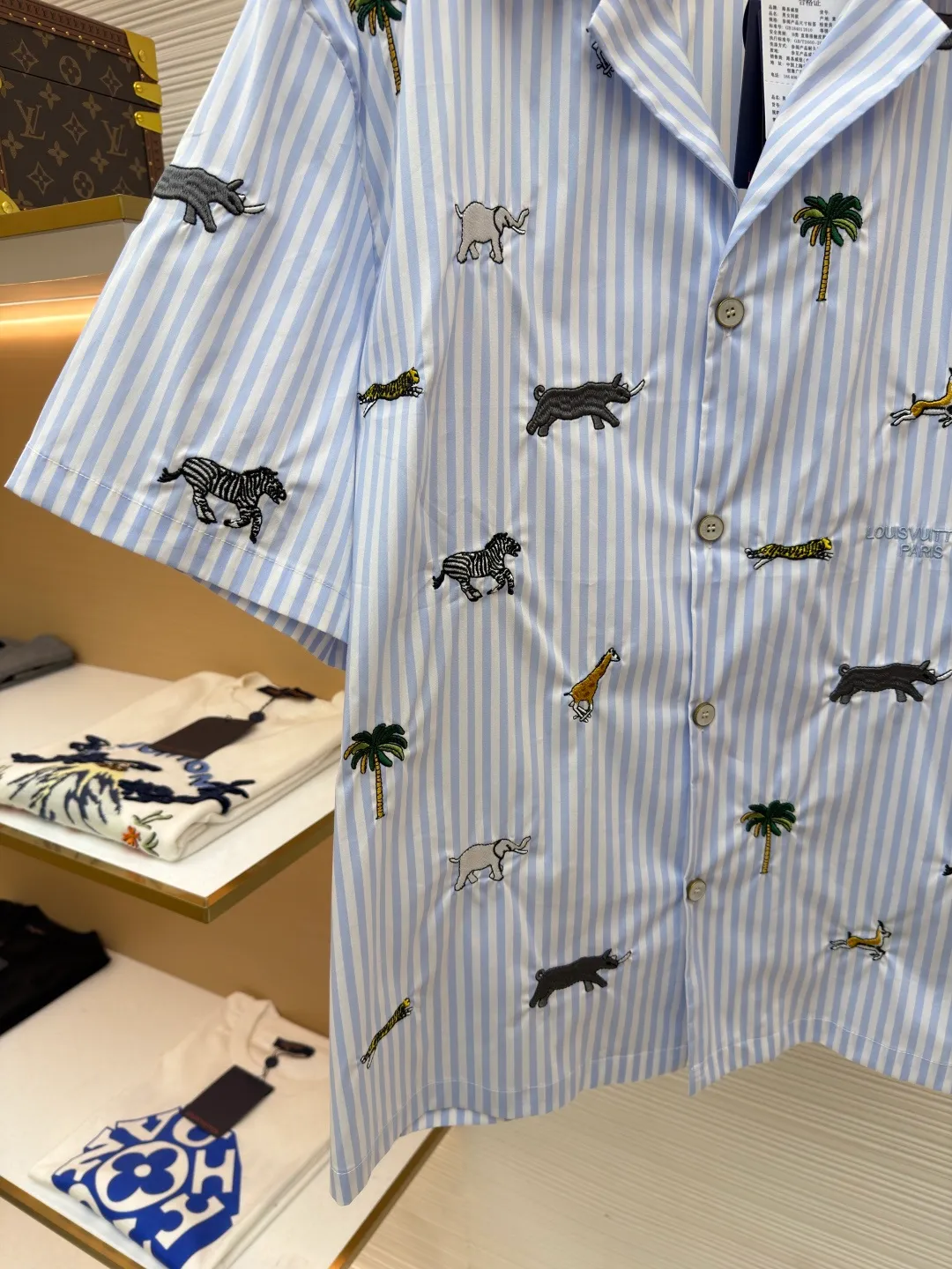 LOUIS VUITTON nostalgic style embroidered striped short-sleeved shirt with animals and plants ●Original version: Purchased and developed by 16815 ●Item number: 1682514-A65 ●Fabric: cotton fabric ●Technology: embroidery production ●Color: blue ●Version: fitted version ●Weight: about 220 grams ●Size: S-M-L-XL ●Description: This LOUIS VUITTON striped animal embroidery short-sleeved shirt is made of high-count pure cotton poplin fabric. After pre-washing process, it feels smooth and breathable. It has both drape and stiffness, and is not easy to wrinkle and deform. The blue and white vertical stripes on the body are woven with yarn-dyed technology, and the texture is clear and does not fade. The animal and coconut tree patterns are presented with sophisticated embroidery technology. The embroidery threads are full of color and the stitches are dense. The patterns are three-dimensional and vivid, forming a rich visual hierarchy with the stripe base. The shirt has a Cuban collar style, with smooth necklines, custom mother-of-pearl buttons at the placket, and a warm texture. The overall shape is loose, the shoulder joints are straight and fine, the cuffs are cuffed with exquisite craftsmanship, custom accessories and three logos are complete, and the details are full of luxury craftsmanship. It is suitable for casual vacations and daily outings, etc. The overall wiring is straight and delicate, the fabric is comfortable and soft, and the color is consistent without color difference. It can be matched with the same style to create a fashionable look and control various occasions. Customized accessories, complete with three standards, same style for men and women!